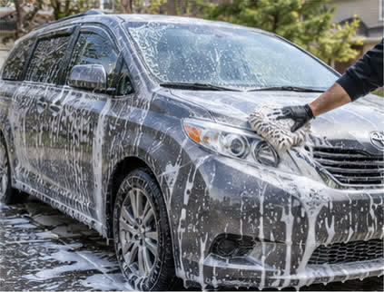 Minivan being hand-washed with a foam mitt